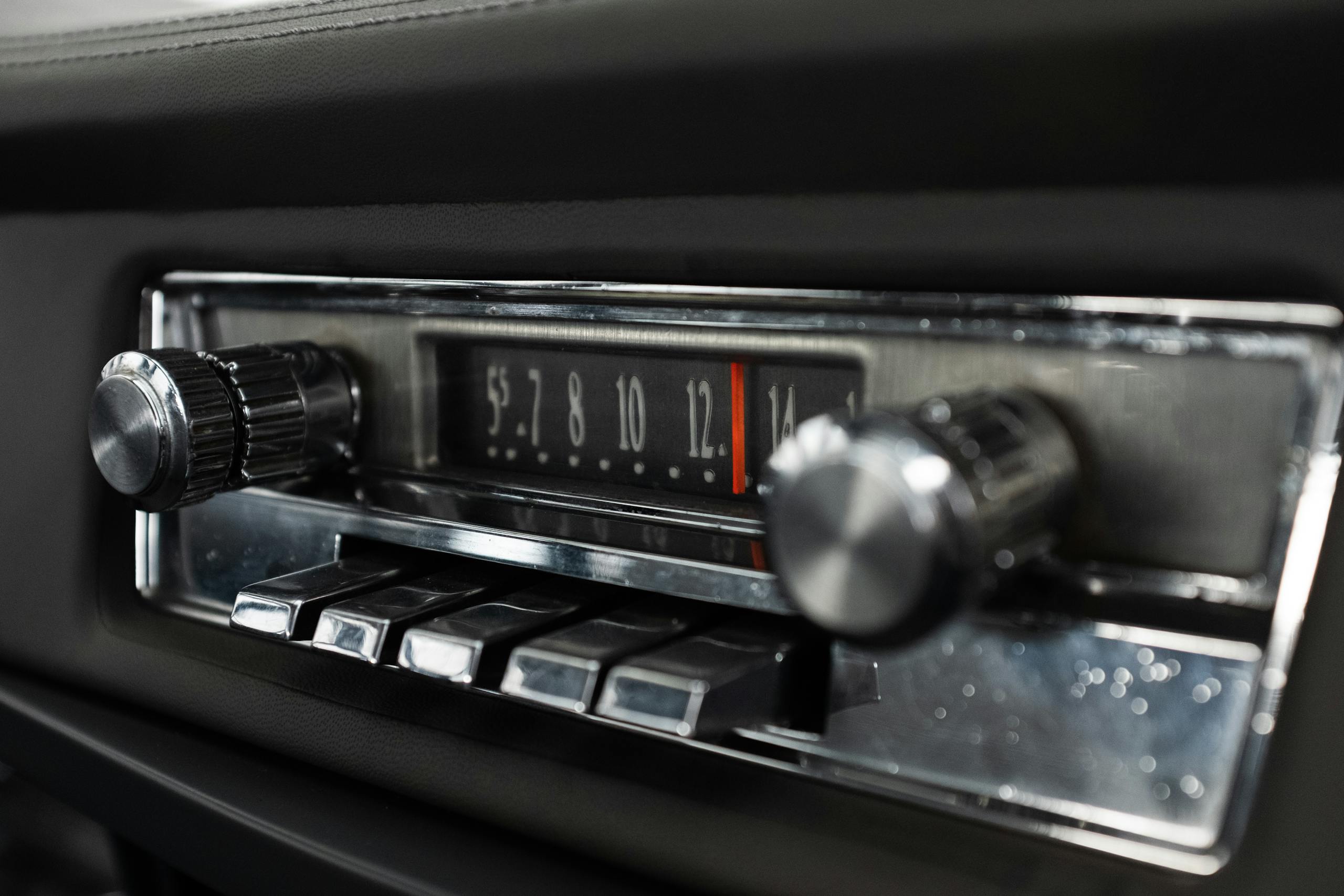 Detailed view of a classic car radio dashboard with chrome knobs and buttons.